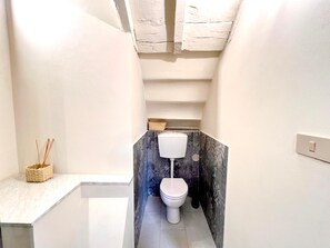 A compact bathroom with a white toilet, a small sink, and a towel rack. - civico 12 appartamento in centro storico (LUCCA)