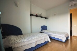A room with two beds, a shelf with decorative items, and a door leading to another room. - Casa ai giardini in front of the ancient wall (LUCCA)