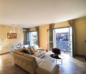A living room with a sofa, a coffee table, and a balcony with a view. - Casa ai giardini in front of the ancient wall (LUCCA)