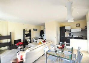 A modern living room with a sofa, a glass dining table, and a kitchen area with appliances. - Casa ai giardini in front of the ancient wall (LUCCA)