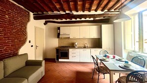 Een gezellige keuken met witte kastjes, een eettafel gedekt voor twee personen en een bakstenen muur.