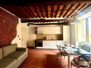 Uma cozinha acolhedora com armários brancos, uma mesa de jantar posta para dois e uma parede de tijolos.