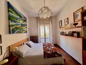 Une chambre à coucher avec un lit, un tableau, un lustre et une bibliothèque.