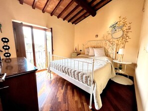 Quarto com cama, mesa de cabeceira, abajur e janela com vista.
