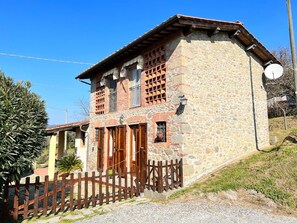 Un bâtiment en pierre avec une clôture en bois, une antenne parabolique et un ciel dégagé.