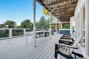 A covered outdoor deck with a table and chairs, a hot tub, and a view of trees. - New Listing, Hot Tub, Arcade Games, Free Attractions, Mountain Views (Gatlinburg)