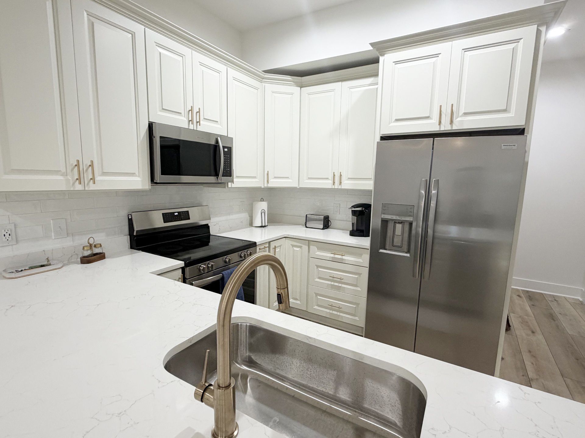 A modern kitchen with white cabinetry, stainless steel appliances, and a marble countertop.