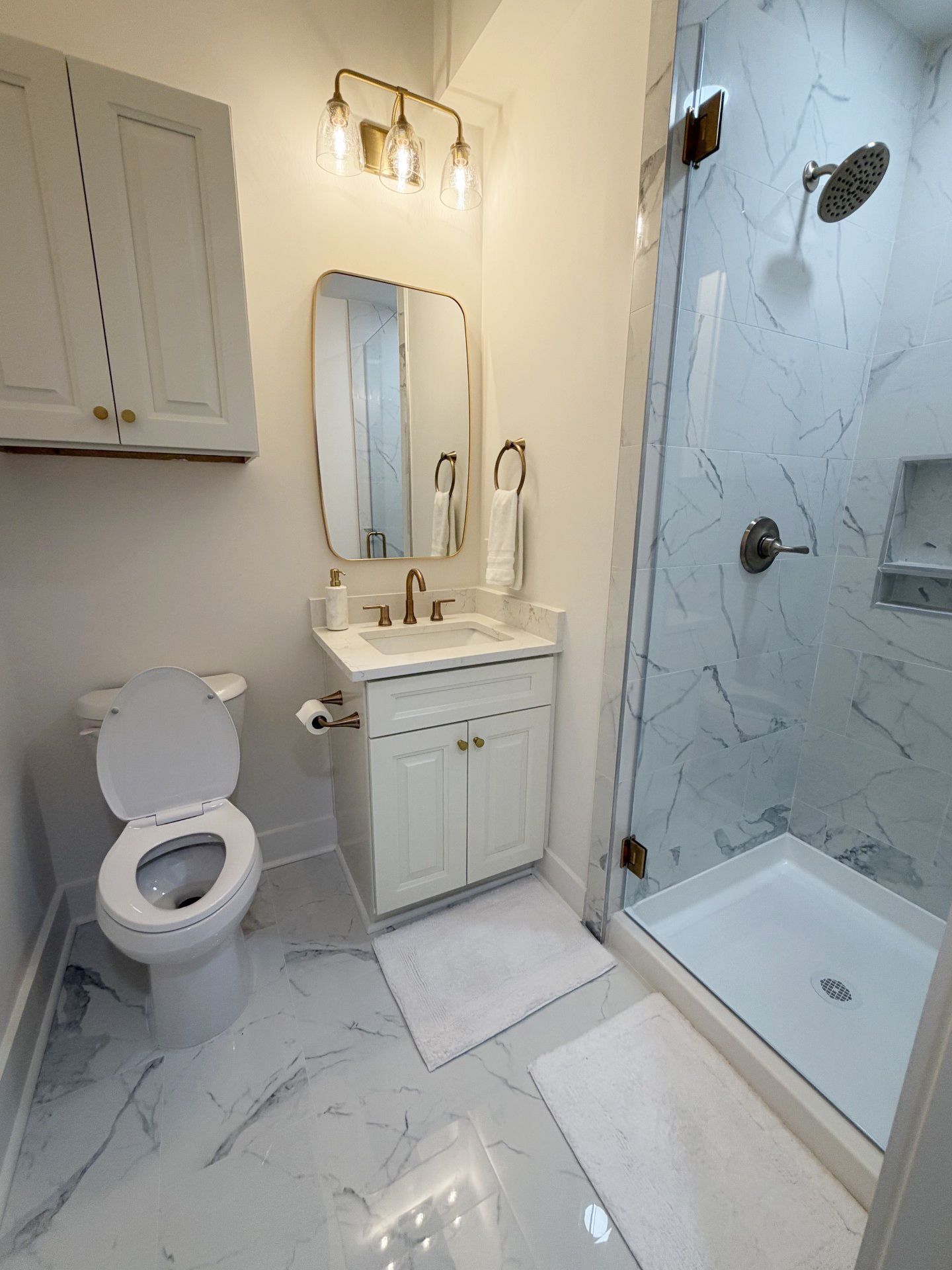 Un baño con inodoro, lavamanos, espejo y ducha.