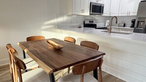 Una cocina moderna con armarios blancos, una mesa de comedor de madera y una isla integrada con pileta.