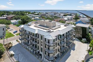 Un immeuble moderne à plusieurs étages, doté d’un toit plat, entouré d’un parking et d’un port de plaisance.