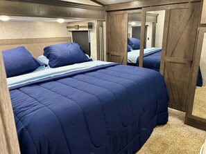 A bedroom with a bed, a wardrobe, and a mirror. - East Tennessee Private Camper Getaway Near Norris Lake (New Tazewell)