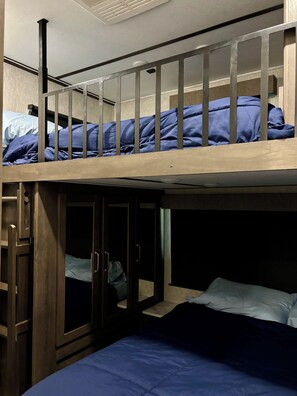 Una cama litera con una cama en la parte inferior y un pequeño espacio cerrado con puerta.
