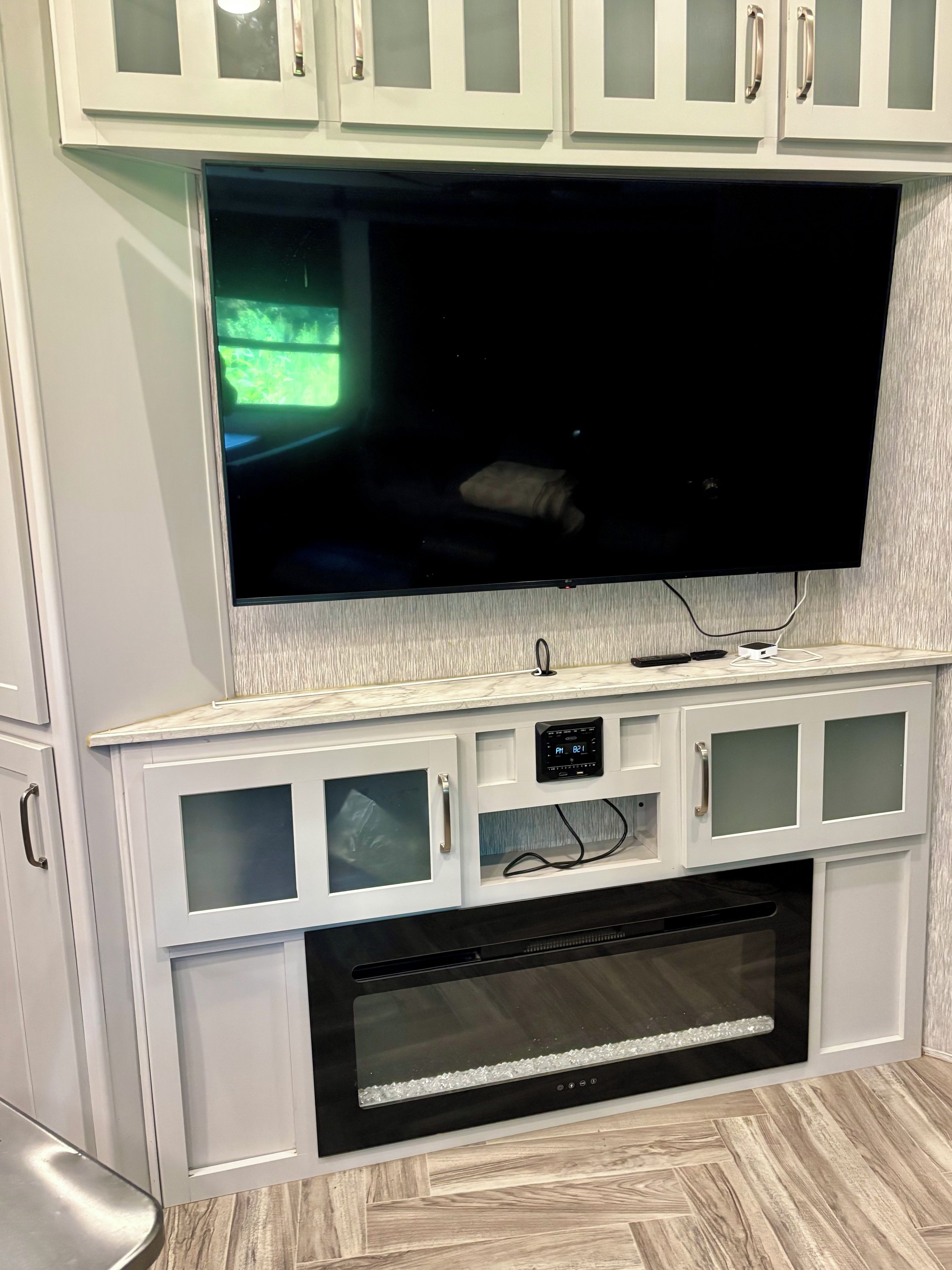 A modern kitchen with a built-in TV, white cabinetry, and a stainless steel oven.
