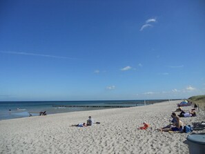 A beach with people sunbathing and playing, a pier in the background, and a clear sky. - Holiday Home in Zingst With Sauna (Zingst)