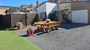 Il s’agit d’une propriété résidentielle dotée d’une allée en gravier, d’un banc en bois, de plantes en pot et d’un garage.