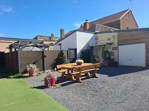 Il s’agit d’une propriété résidentielle dotée d’une allée en gravier, d’un banc en bois, de plantes en pot et d’un garage.