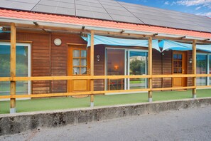 A wooden building with a red roof, large windows, and a covered porch.