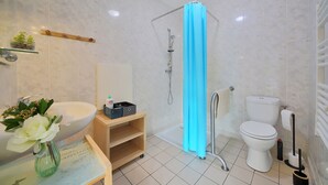 Une salle de bain avec un lavabo, des toilettes et une douche, le tout de couleur blanche.