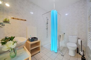Une salle de bain avec un lavabo, des toilettes et une douche, le tout de couleur blanche.