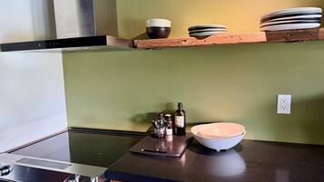 Une cuisine équipée d’une cuisinière, d’un lave-vaisselle et d’un plan de travail sur lequel se trouvent un saladier et des bouteilles.