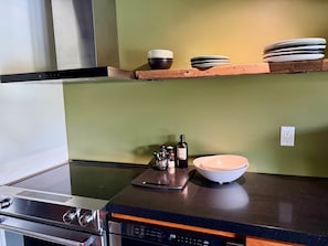 A kitchen with a stove, a dishwasher, and a countertop with a bowl and bottles. - Raven Cove: 5BR Lakefront Home w/ Private Hot Tub (Mina)