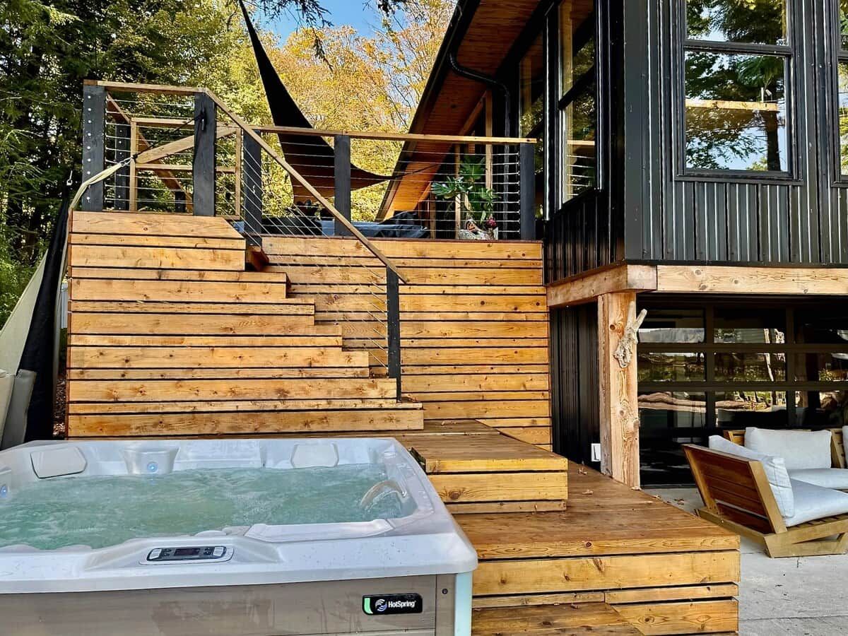 A wooden deck leading to a building with a hot tub in the foreground.
