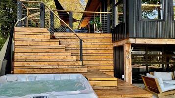 A wooden deck leading to a building with a hot tub in the foreground.