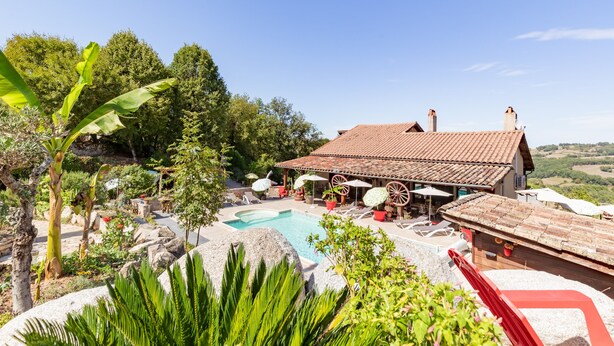 Un espace piscine avec des chaises longues, un coin salon abrité et une vue sur le paysage environnant.