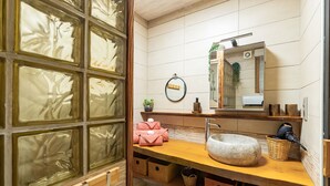 Une salle de bain avec un meuble-lavabo en bois, un vasque en pierre et un miroir.