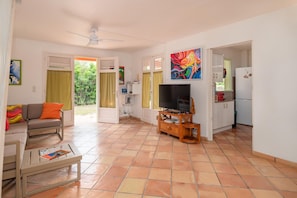 A living room with a sofa, coffee table, TV, and a dining area with a table and chairs. - Villa Devaki - Piscine Privée (Saint-Francois)