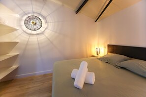 A hotel room with a bed, a headboard, a bedside table with a lamp, and a wall-mounted light fixture. - L'entre'Potes - Piscine Privée (Nalliers)