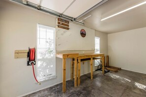 A workshop with a pegboard, a wooden workbench, and a red hose. - The Well Spoke Inn | Bike to Downtown + Coler (Bentonville)