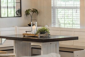 A dining table with a candle, a plant, and a vintage suitcase. - The Well Spoke Inn | Bike to Downtown + Coler (Bentonville)