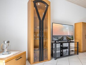 Ein Zimmer mit einem Holzkabinett, einem Kabinett mit Glastür, einem Flachbildfernseher und einem weiteren Kabinett mit Glasfront.