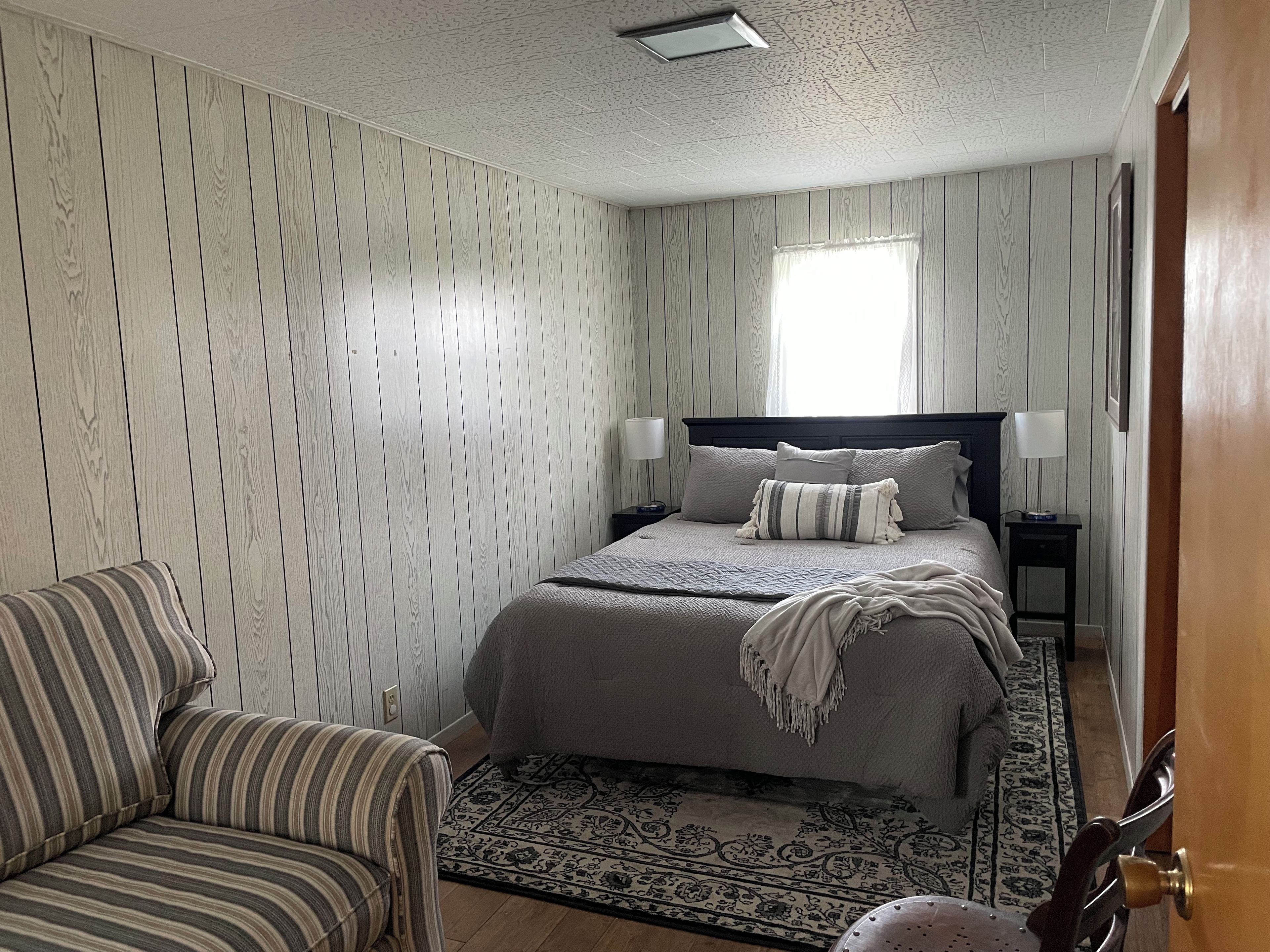 Une chambre à coucher avec un lit, des tables de chevet, une chaise et un tapis à motifs.