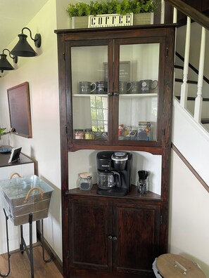A wooden cabinet with glass doors, containing a coffee maker, mugs, and jars. - Enjoy a stay on the farm by Lake Wilhelm and Goddard State Park in Sandy Lake PA (Sandy Lake)