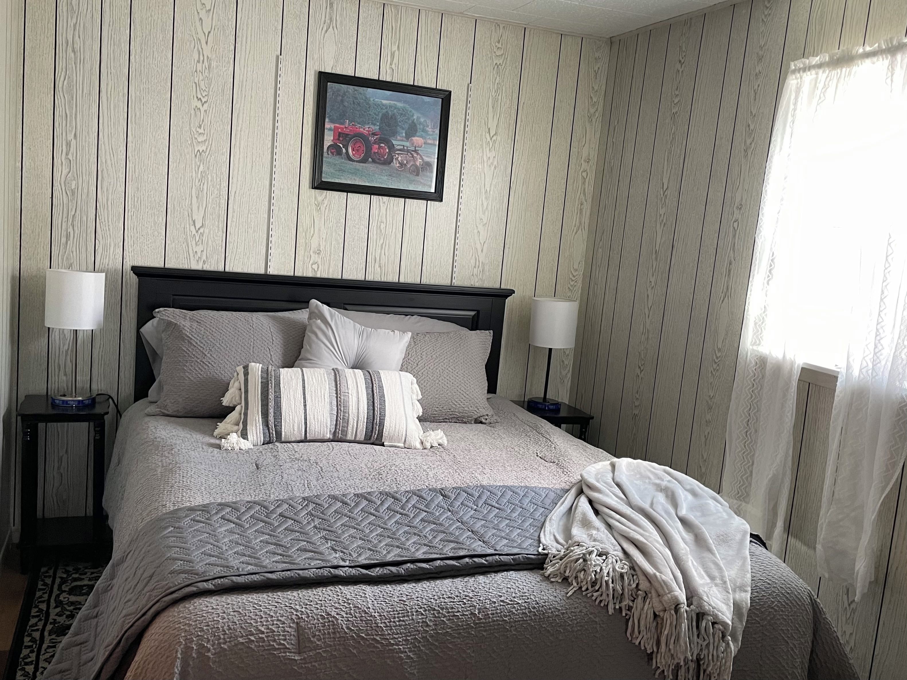 A neatly made bed with a quilted cover, two bedside lamps, and a framed picture on the wall.