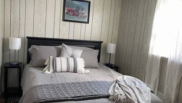 A neatly made bed with a quilted cover, two bedside lamps, and a framed picture on the wall.