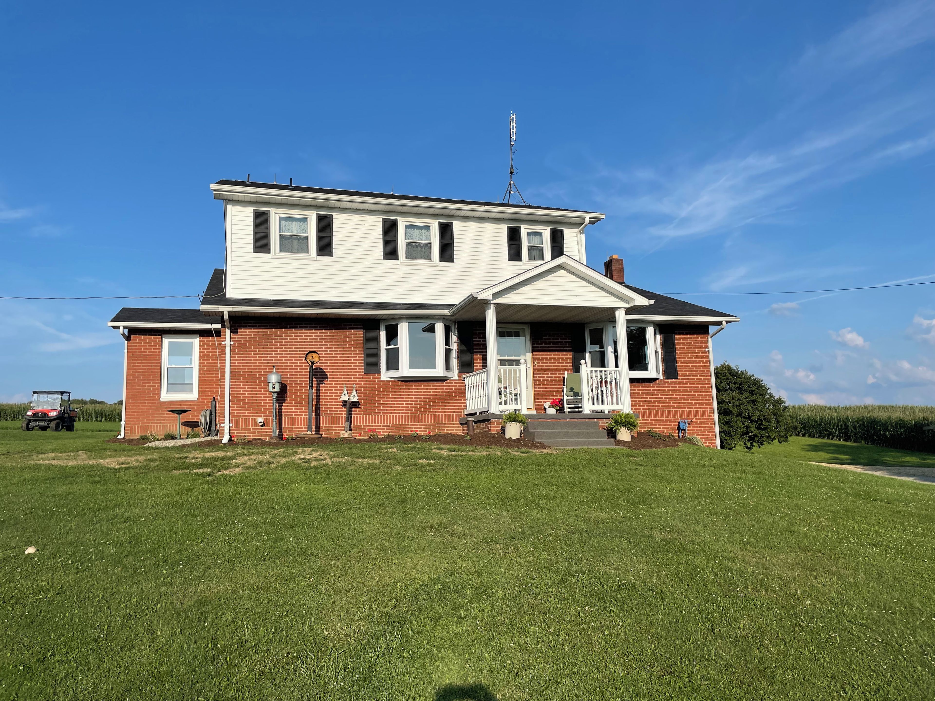 A two-story house with a front porch, a satellite dish, and a lawn in front.
