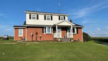 A two-story house with a front porch, a satellite dish, and a lawn in front.