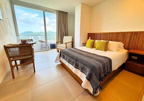Una habitación de hotel con una cama grande, un escritorio y vistas al exterior.