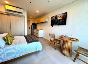 Un dormitorio moderno con cama, mesita de noche y comedor con mesa y sillas.