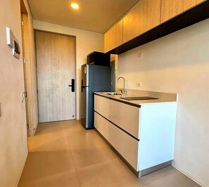Una cocina compacta con un refrigerador integrado, un fregadero y una puerta que da a otra habitación.