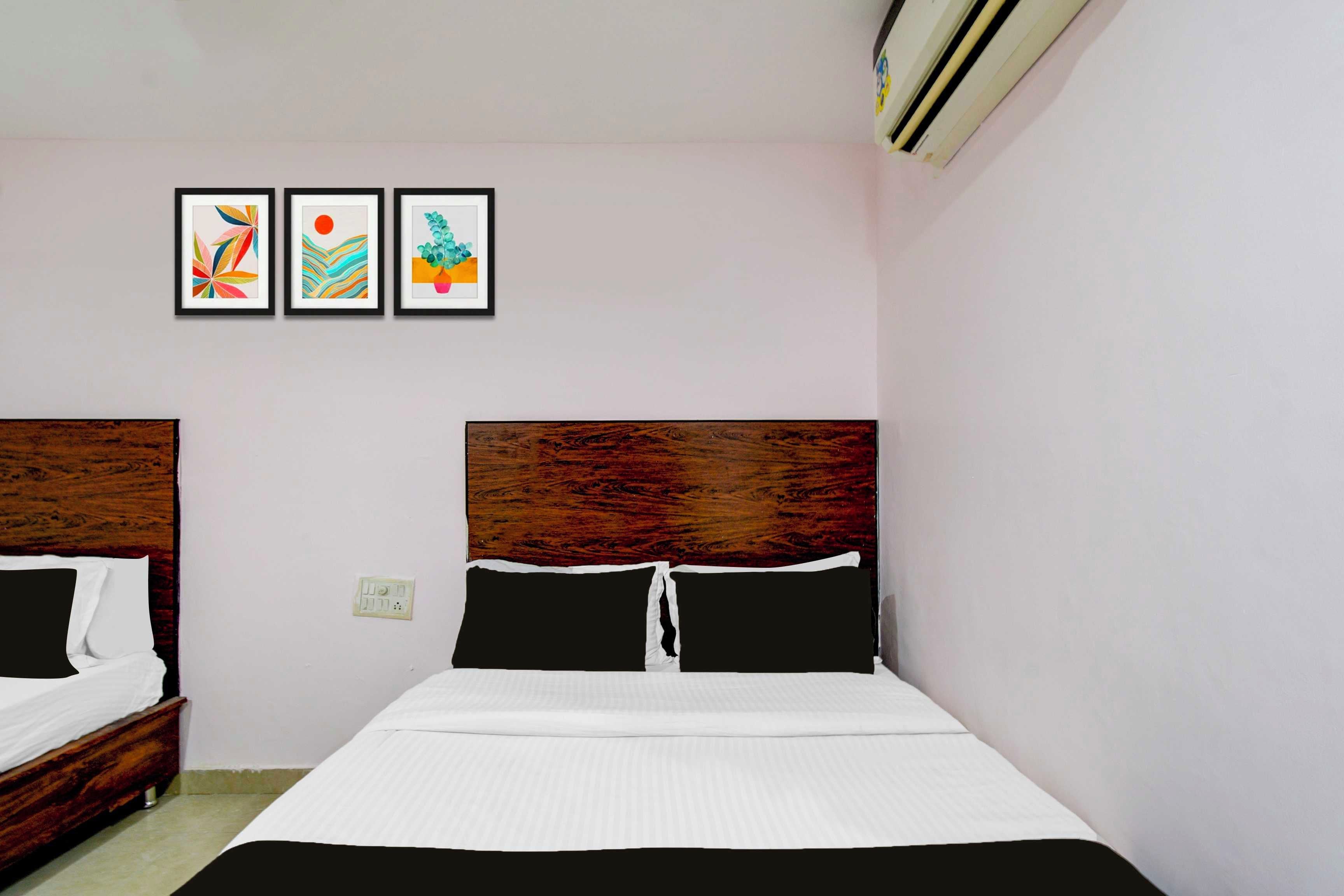 A bedroom with a wooden headboard, a bed with white bedding, and three framed artworks on the wall.
