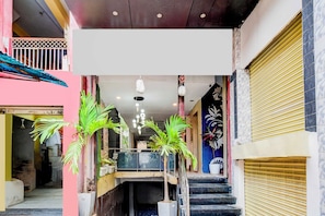 A multi-level commercial building with a staircase, potted plants, and a closed shutter on the right. - Townhouse Nampally Metro Station Hyd (Hyderabad)