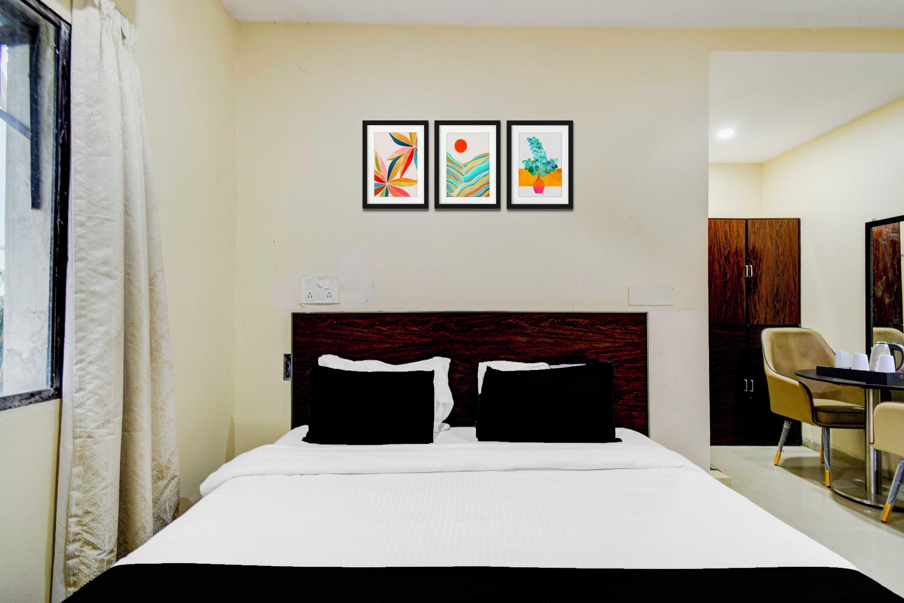 Habitación de hotel con cama, escritorio y tres cuadros en la pared.