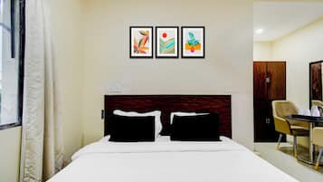 Habitación de hotel con cama, escritorio y tres cuadros en la pared.