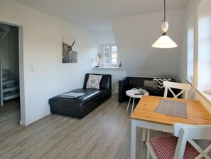 A compact living space with a sofa, a dining table, and a pendant light. - 8, Dorpstraat 9 (Wyk auf Foehr)
