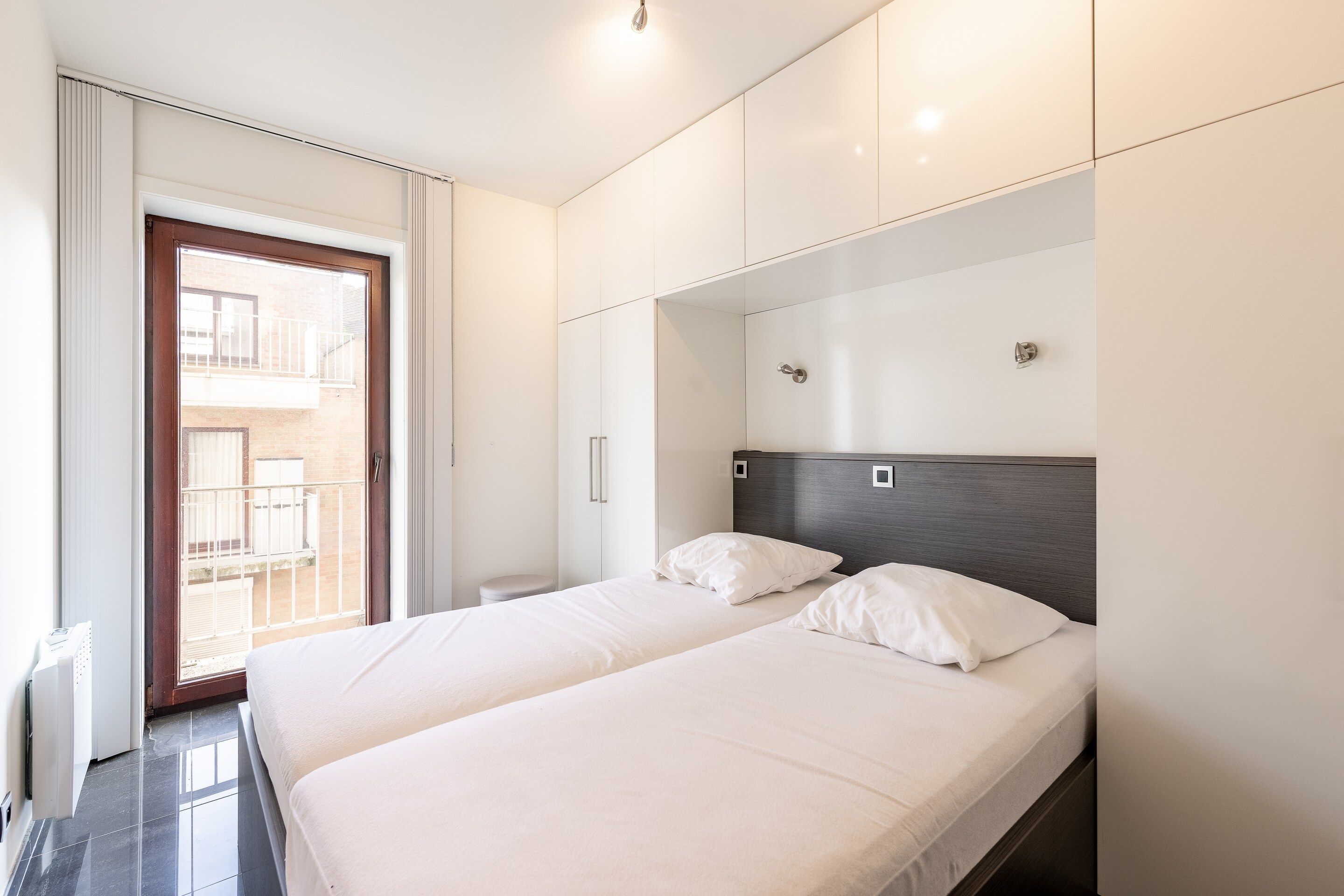 A hotel room with a bed, a wardrobe, a bathroom, and a balcony.
