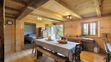 Un intérieur en bois comprenant une table à manger, des bancs, une horloge et une fenêtre.